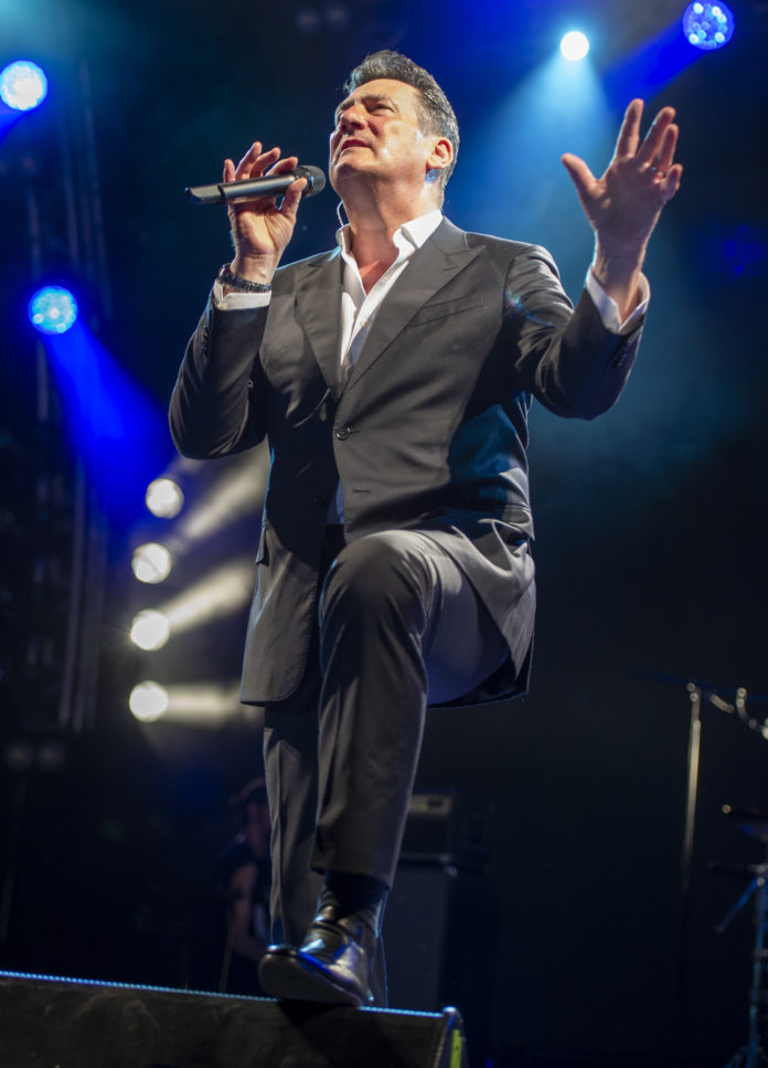 Tony Hadley che canta in concerto con microfono in mano