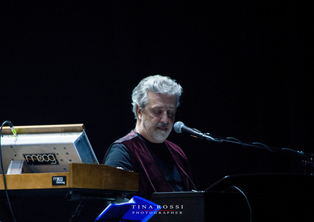 primo piano di flavio premoli, seduto dietro le tastiere, con gilet granata e maglia nera