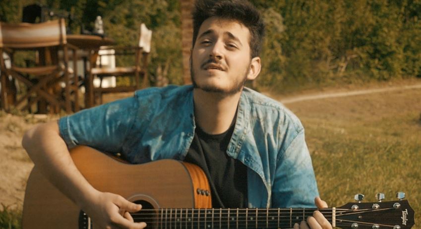 primo piano di ivan Bentivoglio, che indossa un camiciotto di jeans, intento a suonare la chitarra acustica