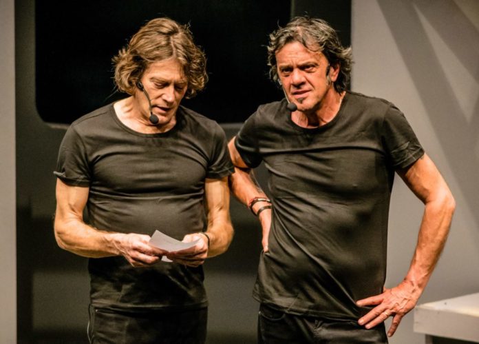 Marco e Mauro, vestiti con t shirt marroni, parlano durante uno spettacolo