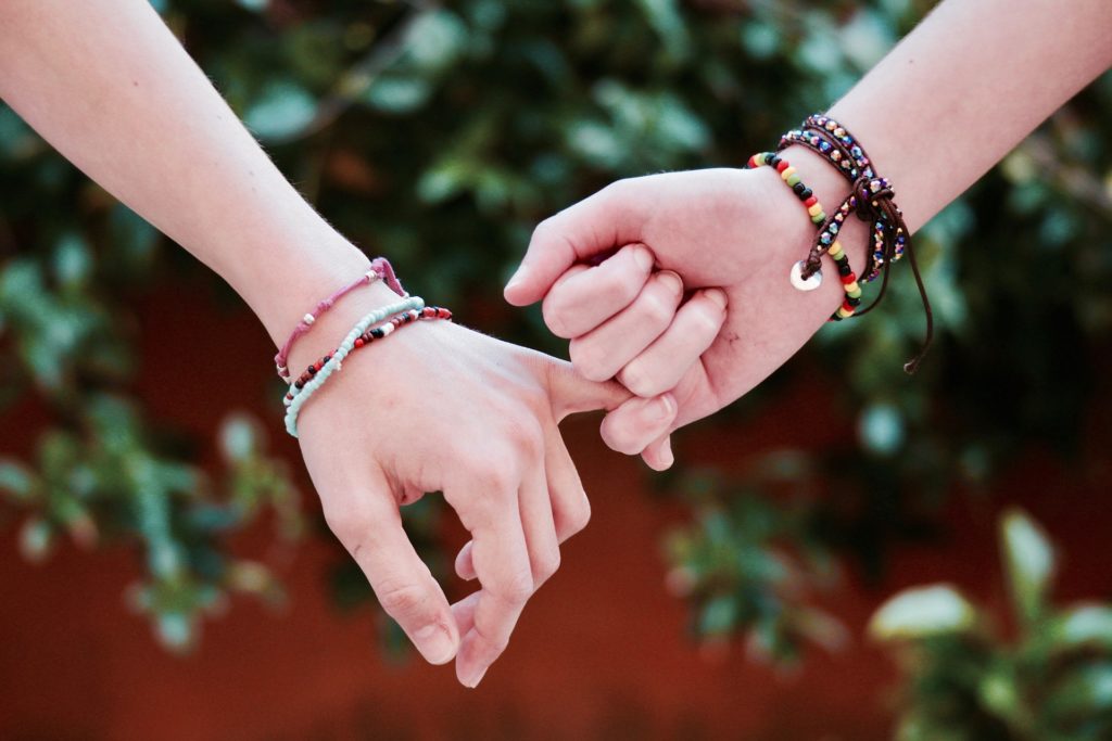 due mani di ragazze che incrociano i propri mignoli in segno di amicizia