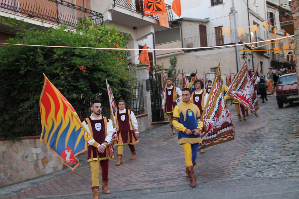 Gli sbandieratori del palio di Bisignao in corteo per le strade con le bandiere in mano
