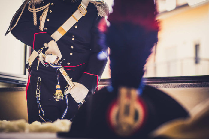 Carabiniere in divisa e in primo piano il cappello col pennacchio