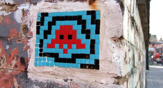 un pezzo del mosaico della caccia al tesoro di Space invaders disegno di un astronave rossa incorniciata di strisce blu e nere disegnata sul un muro
