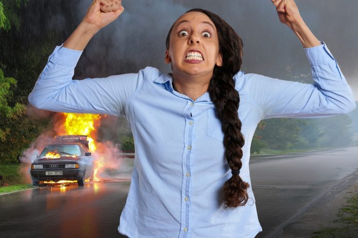 Assemblea di condomio: la foto esprime una minaccia con una donna che urla in primo piano, con camicia di jeans, iuna lunga treccia sulla parte destra, i pugni alzati e i denti stretti, sullo sfondo un auto che brucia
