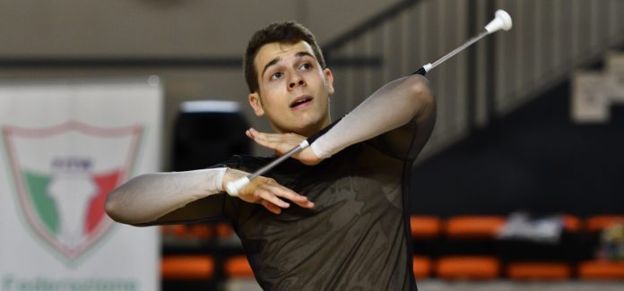 Luca Fasano terzo classificato agli Europei di Twirling, durante l'esibizione, indossa una maglia marrone e tiene tra le mani il bastone da twirling