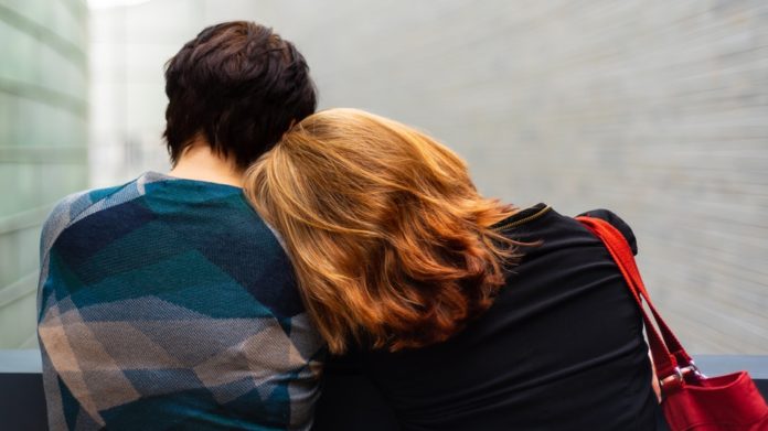 Non sono una signora - Un coppia ripresa di schiena abbracciata, lui ha i capelli neri, lei i capelli lunghi e biondi