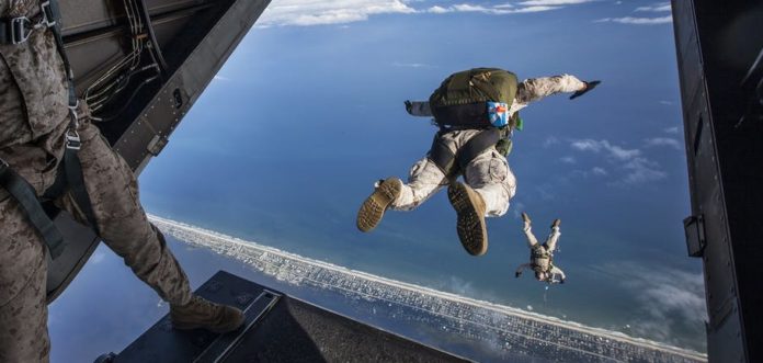 ex alto fulgor è il motto della brigata folgore dell'esercito italiano. nella foto un paracadutista si sta per lanciare da un aereo militare e guarda il suo compagno cche si è appena lanciato nel vuoto