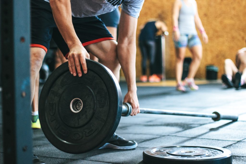 un uomo chino mentre monta dei pesi su un bilancere in palestra