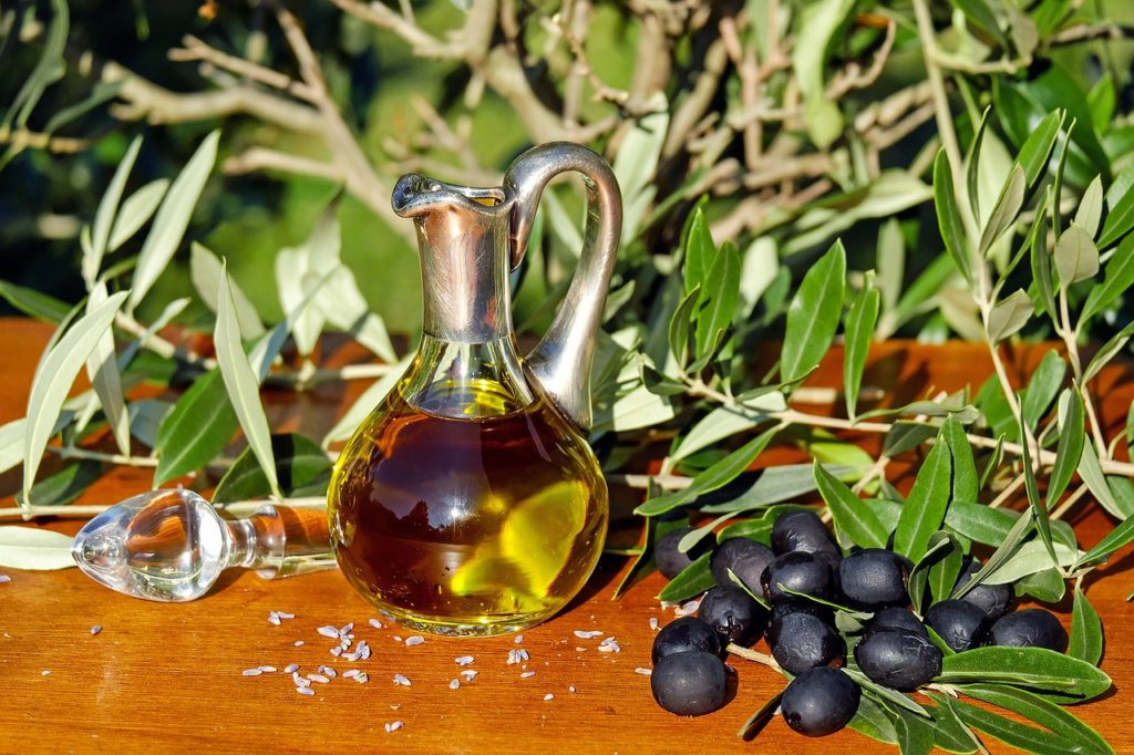 Fiera di Carmagnola. Nella foto un'ampolla di olio appoggiata su un tavolo e intorno dei rami d'ulivo e delle olive