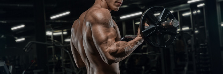 Un uomo muscoloso in palestra che sta sollevando dei pesi