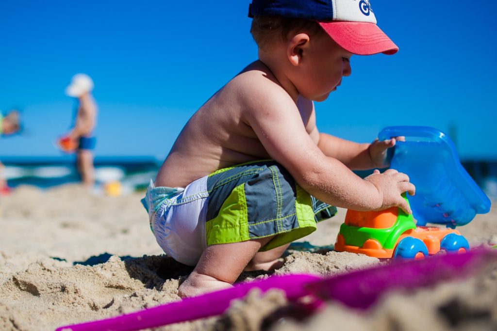 Un bambino che gioca in riva al mare con formine colorate