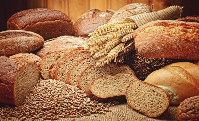 pagnotte di paneintere e tagliate a fette con appoggiate delle spighe di grano