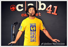un attore e famoso comico Baz durante la sua serata al Cab. ripreso sul palco con microfono e maglietta gialla con scritta super baz