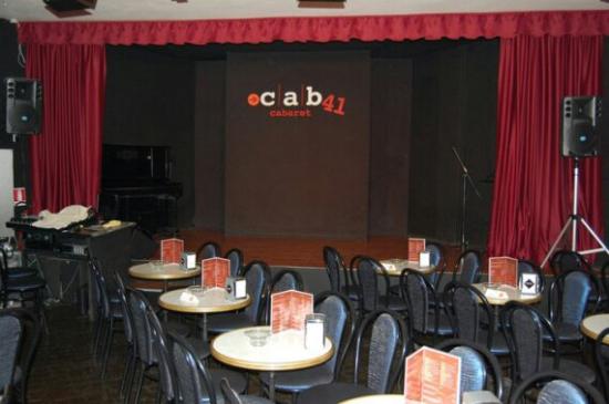 interno del locale cab 41. il palco con il sipario rosso e tutti i tavolini con le sedie nere  a contorno