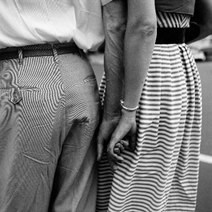 foto in bianco e nero di Vivia Maier, due mani che si intreccano tra un uomo e una donna, voltati di schiena