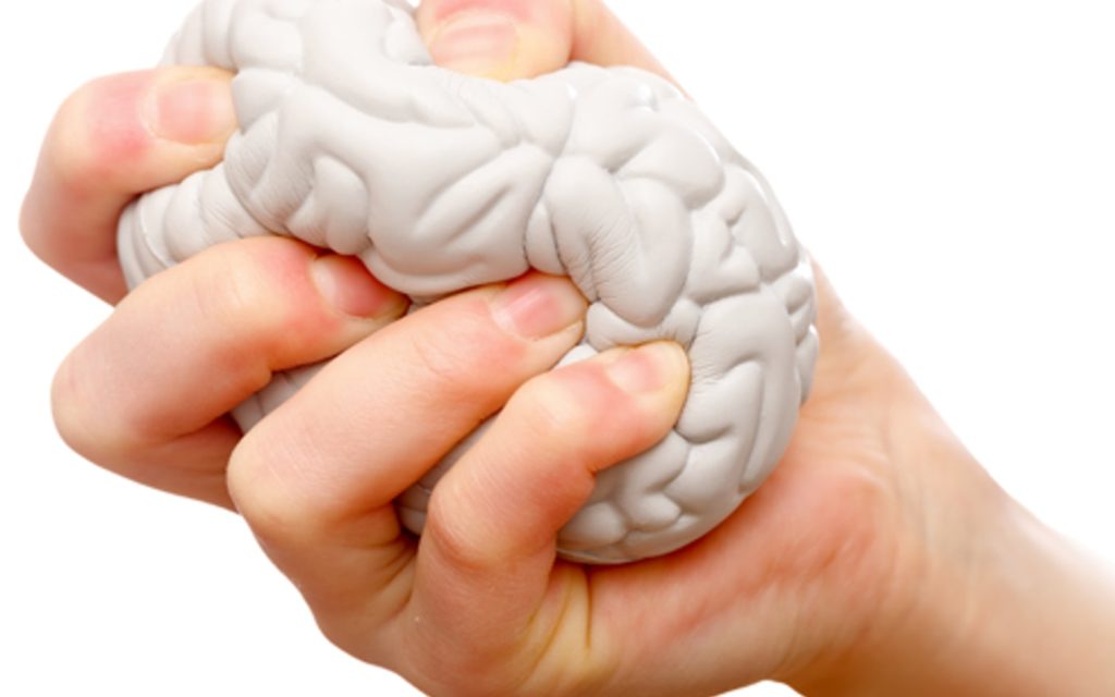 Una mano stringe una pallina antistress a forma di cervello