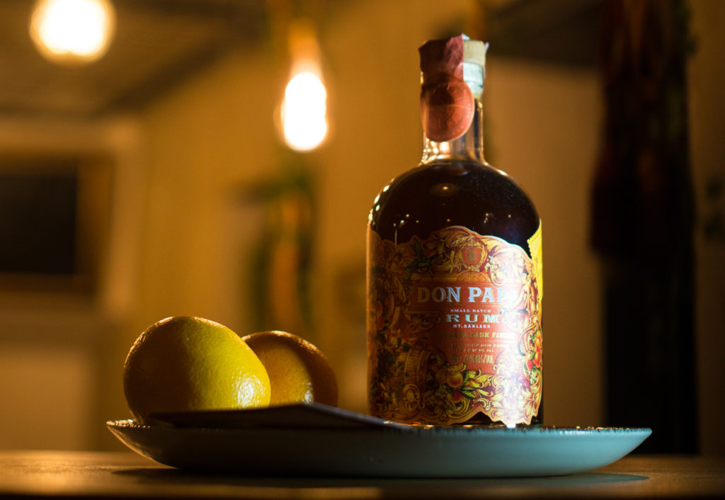 una bottiglia di rum Don Papa appoggiata su un vassoio verde e affianco un lime