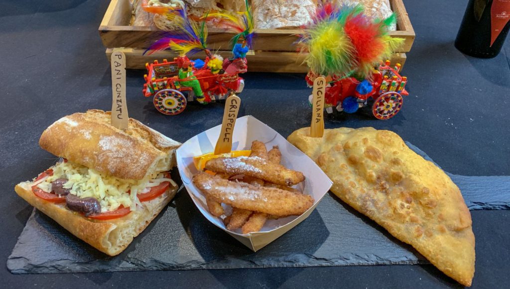 Sicily Fest London con un paniee quadrato di prodotti tipici siciliani, il classico carrretto e delle vaschette con del cibo