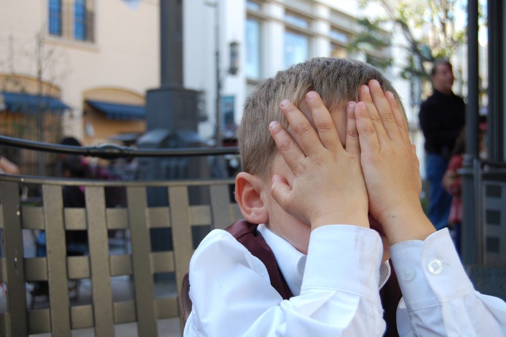 un bambino si copre il volto con le mani per nascondere le proprie emozioni ma è tradito dal linguaggio del corpo