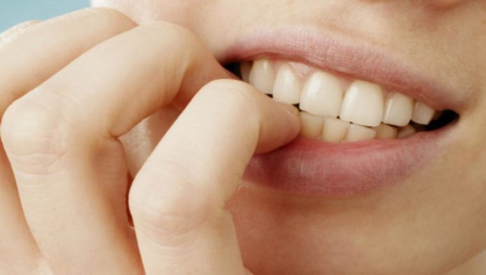 primo piano sulla bocca di una donna che si mangia le unghie per paura