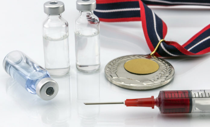 tre flaconi di doping vicino ad una medaglia d'oro e a una siringa con del liquido rosso