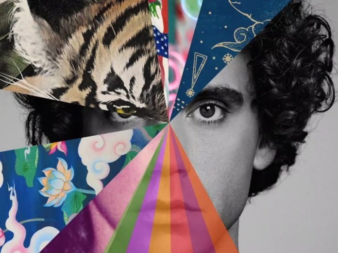 Mika. in primo piano la copertina del nuovo disco My Name Is Michael Holbrook piena dicolori e con la faccia dell'artista in bianco e nero