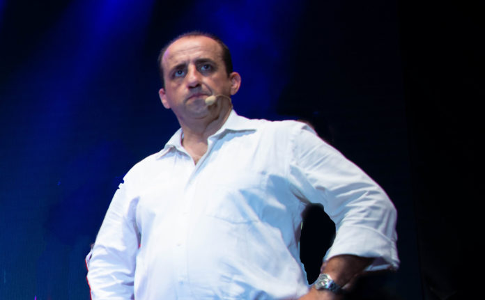 Giampiero Perone con camicia bianca, jeans e microfono ad archetto