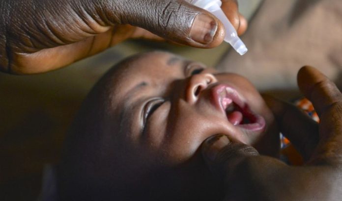 un neonato di colore riceve per bocca da un botticino il vaccino per la poliomelite in occasione della giornata mondiale della polio