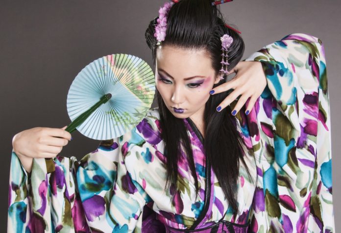 Una donna del giappone indossa un kimono viola a fiori e impugna un ventaglio rotondo come modella per marco polo