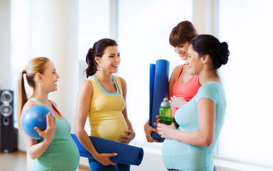 quattro donne in gravidanza con dei tubi d'allenamento in mano, chiacchierano in palestra