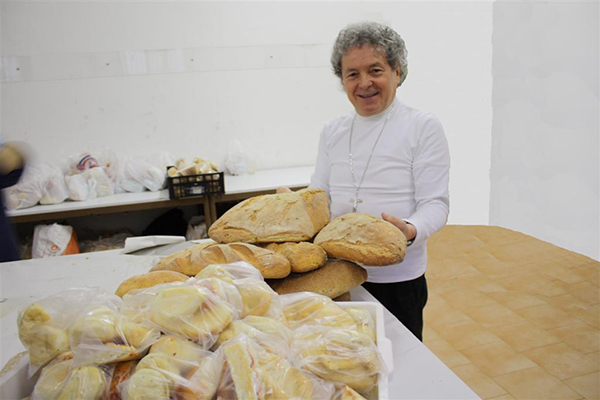 Don Adriano aiuta i poveri con delle pagnotte di pane