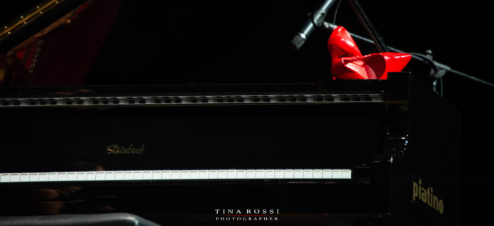 due scarpe rosso indelebile appoggiate su un pianoforte simbolo della violenza sulle donne