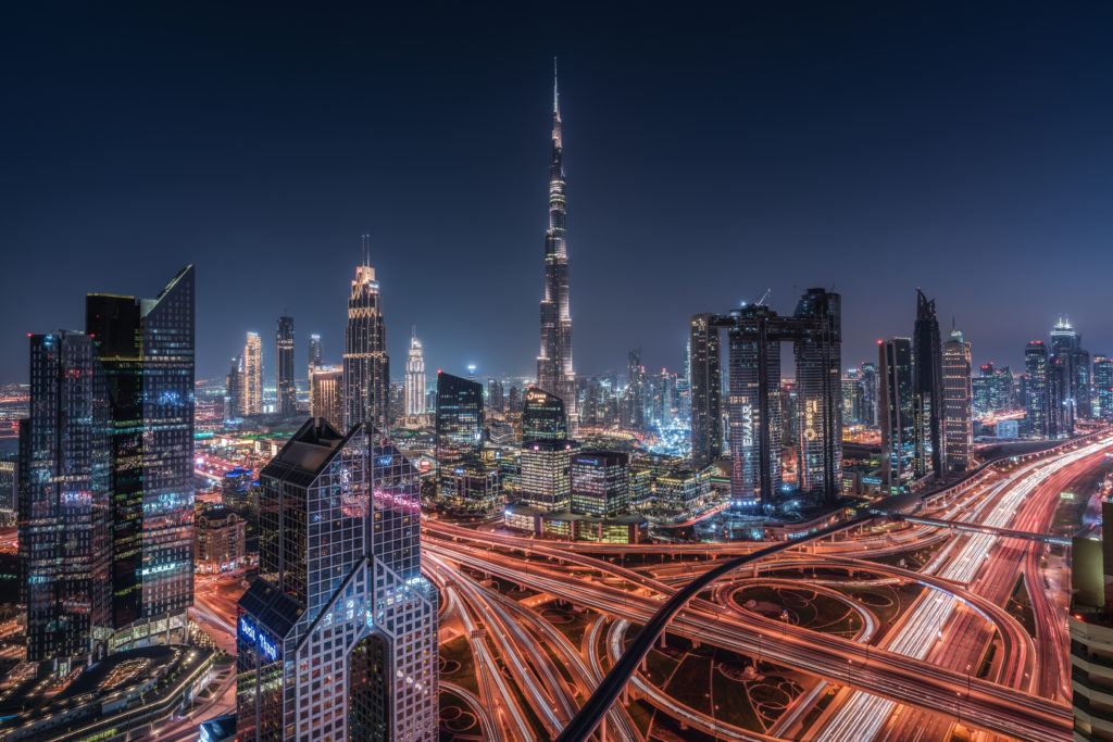 una veduta notturna della città di Dubai grattacieli illuminati e le strade che si aggrovigliano sembrano linee rosse