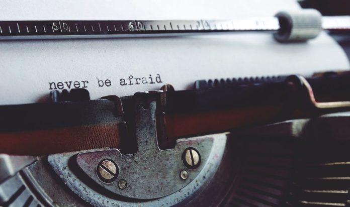 Giornalista vecchia maniera: in primo piano una macchina da scrivere, con la scritta 