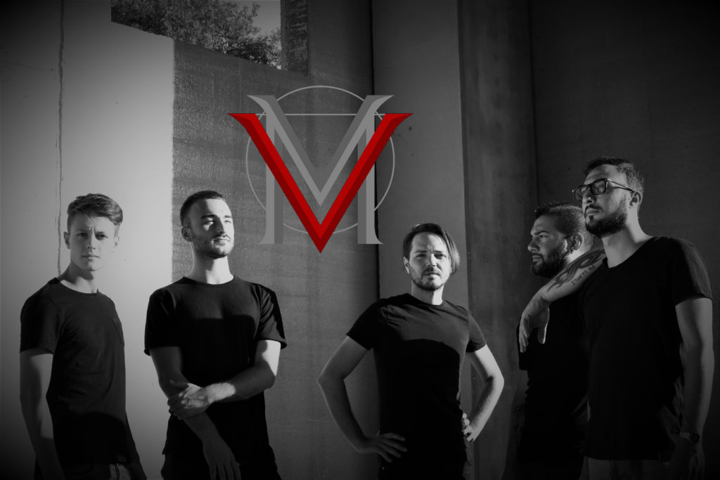 In fondo veramadre in una foto in bianco e nero, tutti vestiti con t shirt nera e pantalone nero, con il loro logo una "v" rossa e una "m" grigia, in mezzo alla foto
