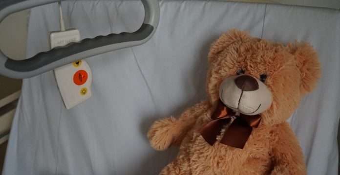 un orsetto di peluche sdraiato in un letto di ospedale