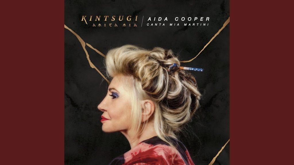 copertina album kintsugi di Aida Cooper, di profilo, vestita con kimono giapponese, i capelli raccolti sulla testa, sfondo nero e oro