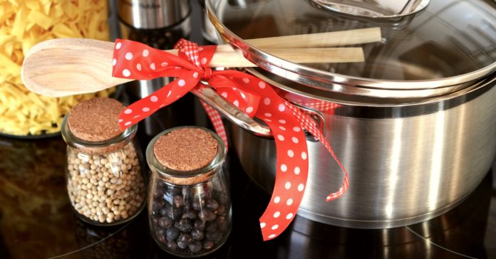 meet in cucina marche una pentola con un coperchio dei cucchiai di legno legati con un nastro rosso a pois e delle ampolle con del pepe in grani