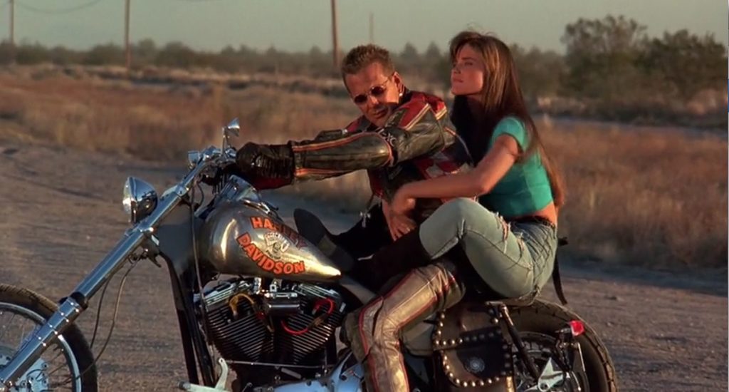 Mickey Rourke in una scena del film Harley-Davidson e Marlboro man, in sella alla moto insieme ad una ragazza