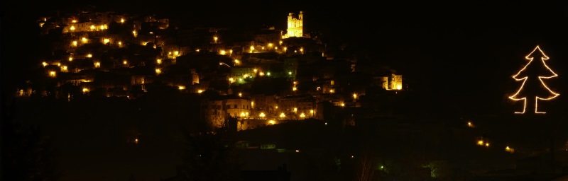 Il borgo di Artena illuminato di notte con a destra l'albero di Natale più grande del mondo, la sua sagoma illuminata disegnata sul lato della montagna. 