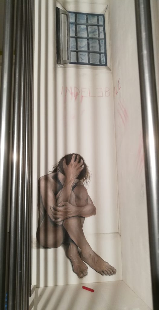 Donna nuda dentro cella con scritta rosso Indelebile opera di Rosalba Castelli 