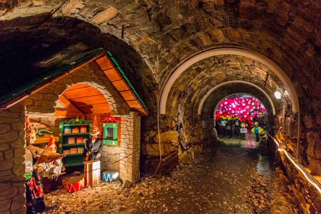 Grotta di Babbo Natale a Ornavasso. Una piccola galleria illuminata che porta verso una casetta di legno abitata da gnomi.