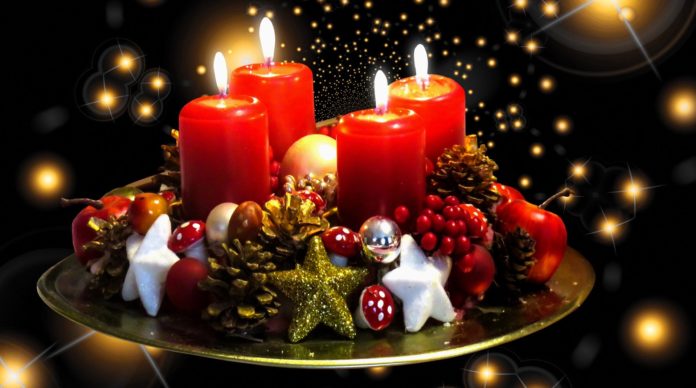 un centrotavola con candele rosse accese per le feste natalizie in allegria, con tante stelline intorno
