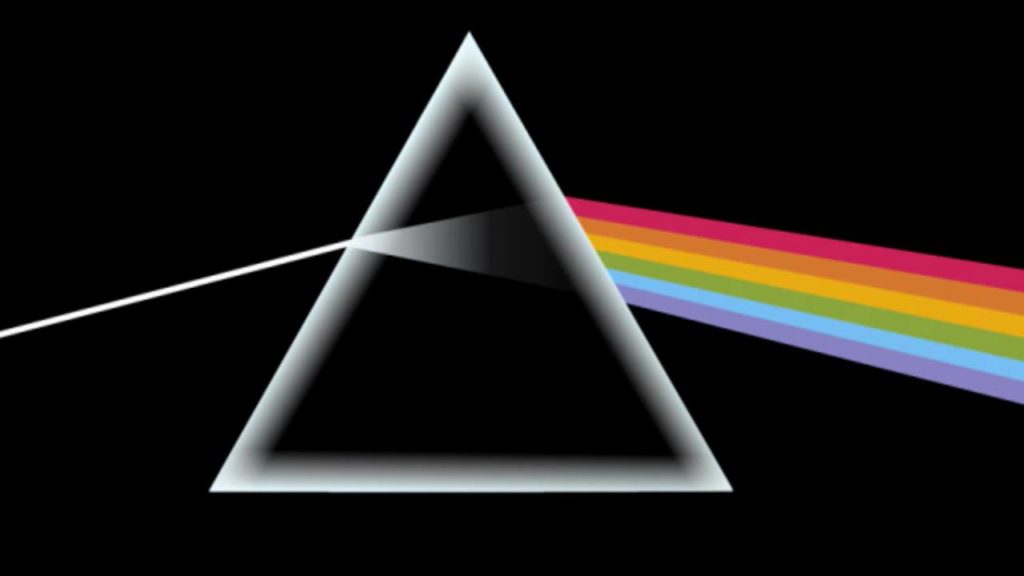 Las vopertina del disco The dark side of the moon dei pink floyd con un triangolo attraversato da un raggio di luce bianca che prosegue al difuori con un arcobalemno, su sfondo nero, l'inizio del nostro space music travel