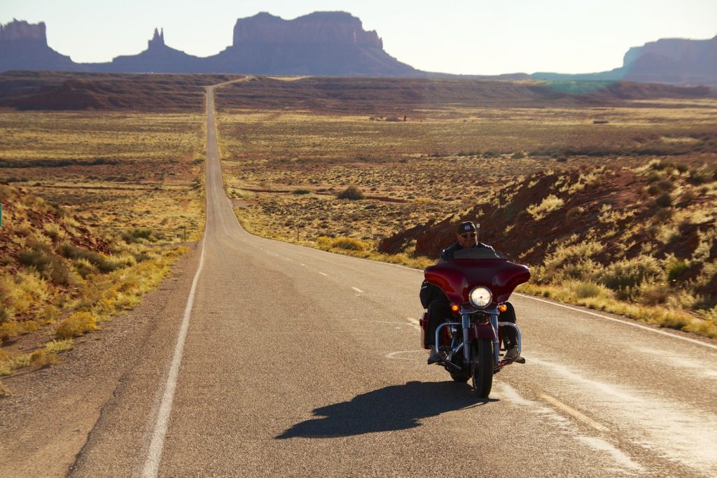Harleysta: nella foto una highway americana in mezzo al deserto, con in primo piano una moto Harley-Davidson