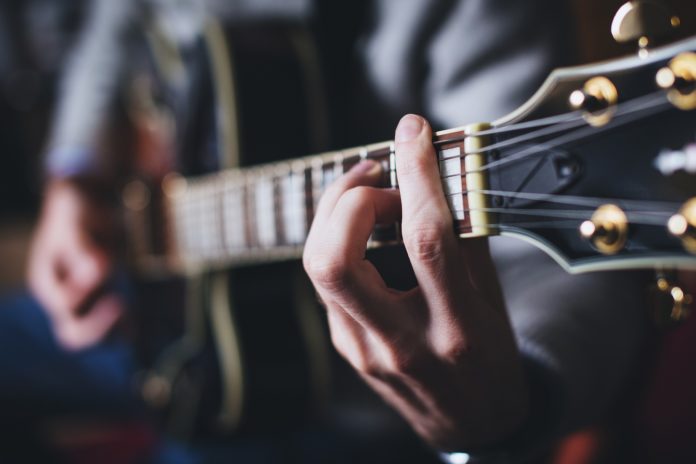 due mani che suonano la chitarra,