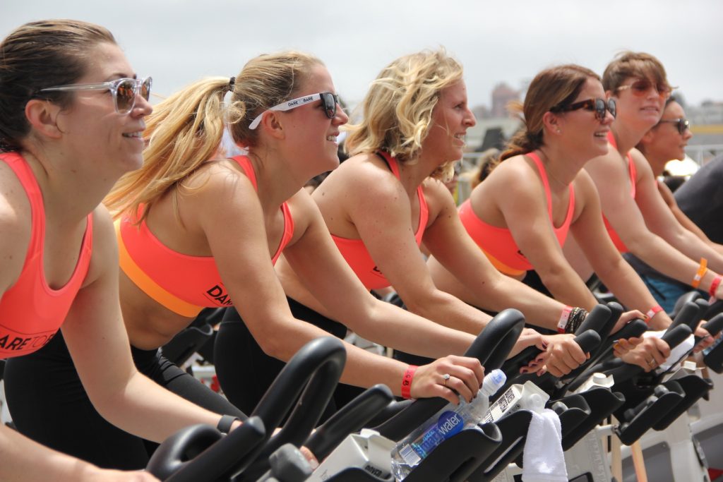 delle ragazze con top arancione fanno cardio su cyclette per migliorare il corpo