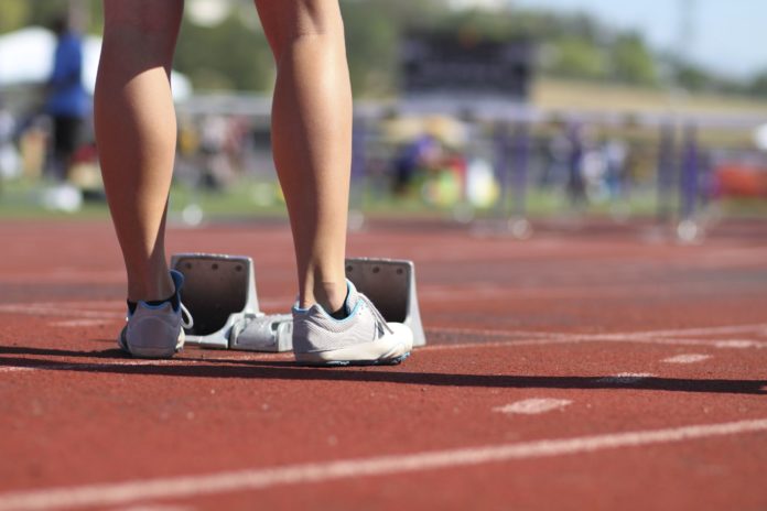 immagine delle gambe di una donna ai blocchi di partenza di una gara di corsa