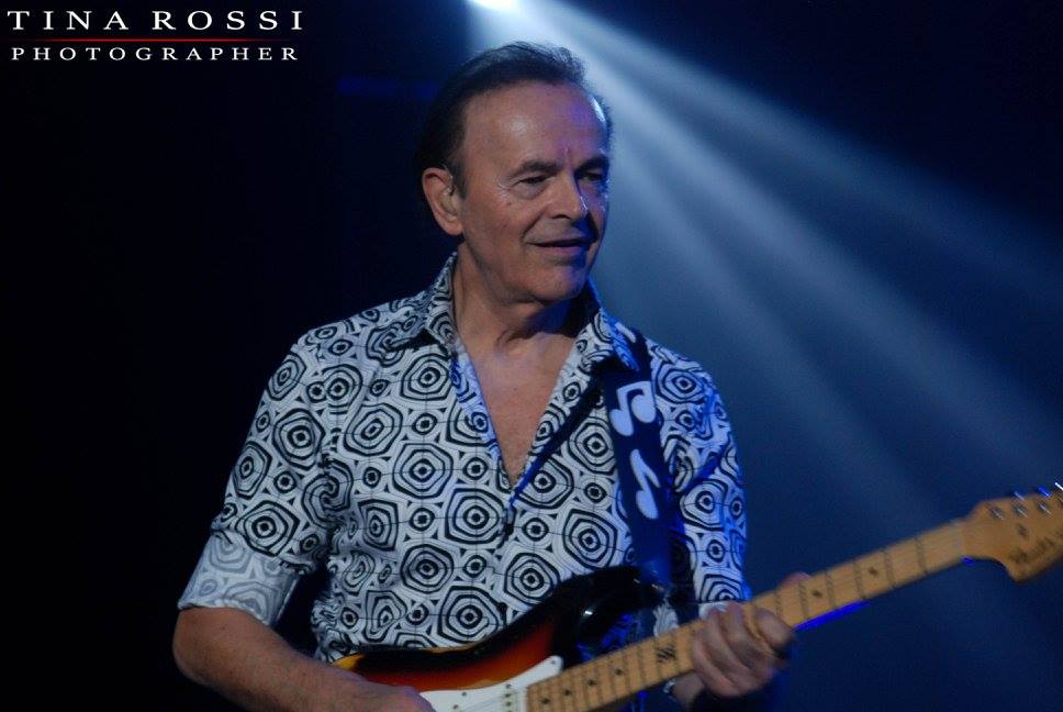 Dodi Battaglia con camicia a fantasia suona la chitarra